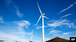 Wind turbines spin to generate electricity power above solar panels in Atlantic City, New Jersey, on Wednesday, February 17, 2021. (AP Photo/Ted Shaffrey)