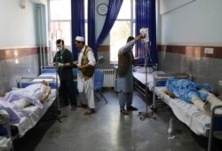 FILE - Afghan men receive treatment at a hospital after a bus was hit by a roadside bomb in Herat province, western Afghanistan, July 31, 2019.