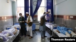 Afghan men receive treatment at a hospital after a bus was hit by a roadside bomb in Herat province, western Afghanistan, July 31, 2019. 