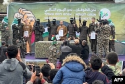 Palestinian Hamas fighters escort Israeli hostages (L-R) Ohad Ben Ami, Eli Sharabi and Or Levy on a stage before handing them over to a Red Cross team in Deir el-Balah, central Gaza, Feb. 8, 2025.