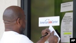 FILE - A resident copies down the Mississippi unemployment benefit website after being unable to enter the state WIN Job Center in north Jackson, Miss., April 2, 2020.