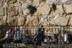 People take cover as a siren sounds a warning of incoming rockets, amid Israeli-Palestinian tension, near the wall surrounding Jerusalem's Old City, May 10, 2021.
