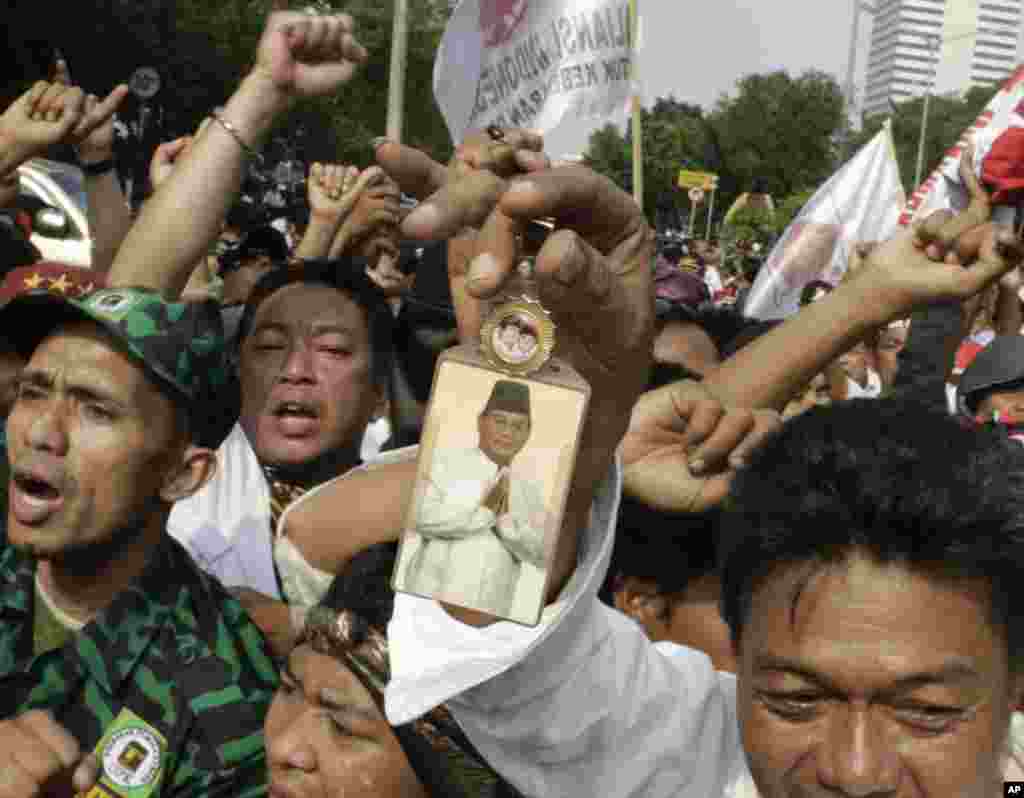 Seorang pendukung memegang potret kandidat presiden yang kalah, Prabowo Subianto, dalam sebuah unjuk rasa dekat Mahkamah Konstitusi di Jakarta (21/8). (AP/Dita Alangkara)