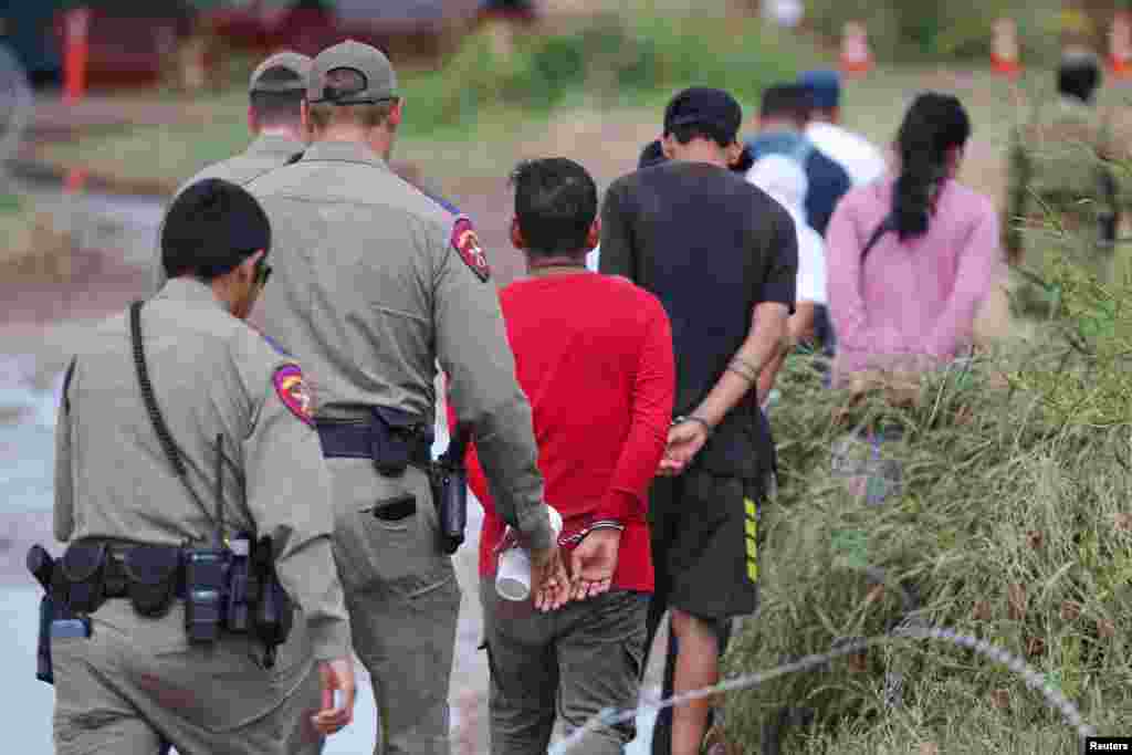 Migrants are detained in handcuffs by authorities after crossing the Rio Grande into the United States in Eagle Pass, Texas, Sept.26, 2023.&nbsp;