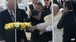 Le pape François, debout sur un bateau de la Garde côtière, jette une couronne de fleurs dans la mer en mémoire des migrants qui n’ont jamais atteint leur destination, lors de sa visite à l'île de Lampedusa, au sud de l'Italie, 8 juillet 2013. 