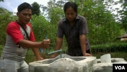 Pak Suharyanto (kiri), peternak kambing di Kabupaten Sleman, Yogyakarta, memeriksa reaktor biogas yang sekaligus dijadikan sarana pengolahan pupuk organik (foto: VOA/Nurhadi).