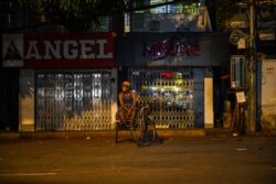 FILE - A trishaw rider waits for customers along an empty road in Yangon, Myanmar, April 9, 2021.