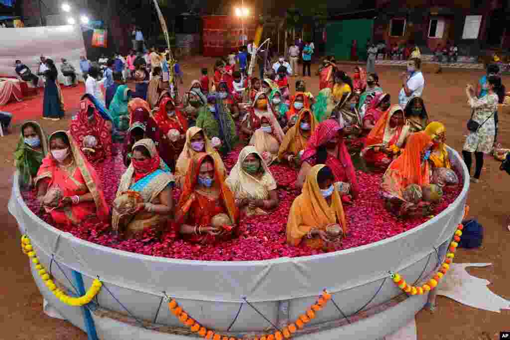 Indian women perform rituals standing inside an artificial pond on Chhat Puja festival in Mumbai, India. 