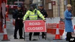 A woman walks by as a police officer adjusts a sign in the London Bridge area of London, June 4, 2017. Police specialists collected evidence in the heart of London after a series of terror attacks.