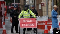 Seorang wanita melintas saat seorang petugas kepolisian mengatur sebuah rambu di kawasan the London Bridge di London, 4 Juni 2017 (foto: AP Photo/Frank Augstein)