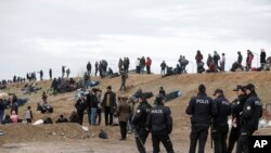 Turkish police stand by migrants camping in Edirne near the Turkish-Greek border, March 5, 2020. 