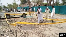 Pakistani security officials examine a crater caused by overnight suicide bombing in the southern city of Sukkur. on July 25, 2013. 