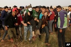 Palestinian protesters evacuate a wounded youth during clashes with Israeli troops along Gaza's border with Israel, east of Khan Younis, Gaza Strip, April 5, 2018. An Israeli airstrike in northern Gaza early Thursday killed a Palestinian, while a second man died from wounds sustained in last week's mass protest.