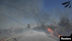 Policajac vozi pored zapaljenih stabala tokom evakuacije civila iz predgrađa grada Kurahove, u oblasti Donjeck, Ukrajina, 16. septembra 2024. (Foto: REUTERS)