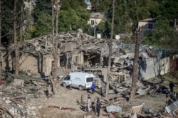 FILE - People look at the destroyed houses a day after shelling by Armenian artillery during fighting over the separatist region of Nagorno-Karabakh, in Ganja, Azerbaijan, Oct. 12, 2020.