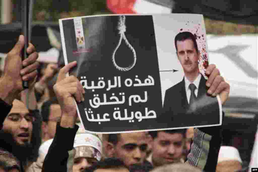 People hold up a poster showing Syrian President Bashar al-Assad during a protest in front of the Syrian embassy in Cairo, Egypt, Friday, Feb. 17, 2012. The poster reads: " That's why this neck was created long". (AP Photo/Amr Nabil)