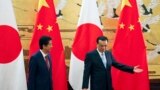 Japanese Prime Minister Shinzo Abe, left, and Chinese Premier Li Keqiang prepare to leave after attending a signing ceremony at the Great Hall of the People in Beijing, Oct. 26, 2018.