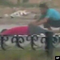 A protester crouches near the body of a man lying on the ground in Hama in this still image taken from video posted on a social media website on August 4, 2011 (Reuters cannot independently verify the content of the video)
