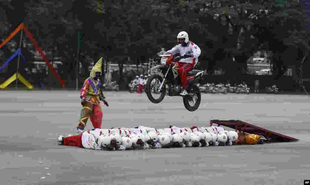 Members of Shwet Ashw, the motorcycle display team of the Indian army, lie in a row on ground as a motorist performs a stunt during the platinum jubilee celebrations of Corps of Military Police in Bangalore, India.