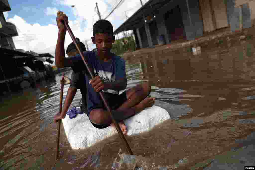 Kids row on a styrofoam block through a flooded street during heavy rains in the Guaratiba neighborhood in Rio de Janeiro, Brazil.