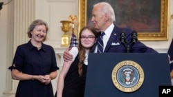 El presidente Joe Biden abraza a Miriam Butorin, hija pequeña de la periodista liberada Alsu Kumarsheva , mientras Elizabeth Whelan, (izq), observa después de pronunciar un discurso sobre un intercambio de prisioneros con Rusia, en la Casa Blanca, el 1 de agosto de 2024.