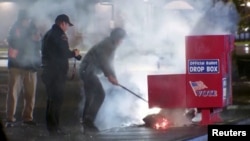 First responders pull out the burning contents of a ballot box after it was set on fire in a suspected arson in Vancouver, Washington, Oct. 28, 2024, in a still image from video. (Evan Bell/ABC Affiliate KATU via Reuters)