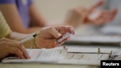 Am election worker checks a voter's drivers license as North Carolina's controversial "Voter ID" law goes into effect for the state's presidential primary election at a polling place in Charlotte, North Carolina, March 15, 2016. 