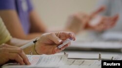 FILE - An election worker checks a driver's license as North Carolina's controversial "Voter ID" law goes into effect for the state's presidential primary election in Charlotte, March 15, 2016. An appeals court nullified most of the law in July.