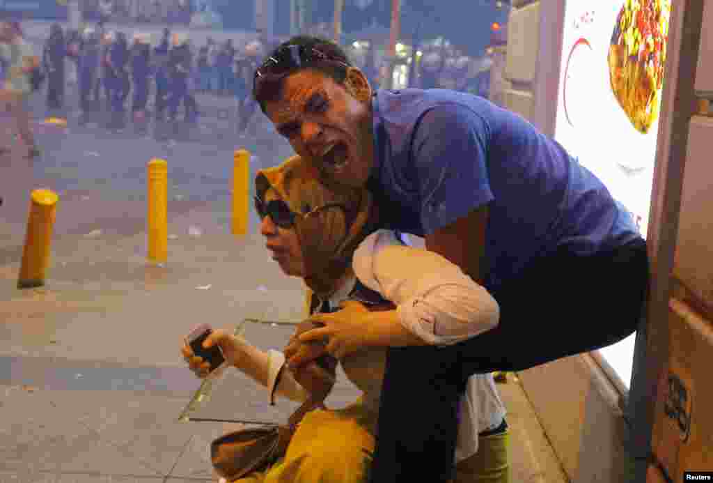 A couple affected by tear gas used by riot police to disperse demonstrators reacts in central Istanbul, Turkey, July 20, 2015.