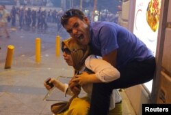 FILE - A couple, affected by tear gas used by riot police to disperse demonstrators, reacts in central Istanbul, Turkey, July 20, 2015.