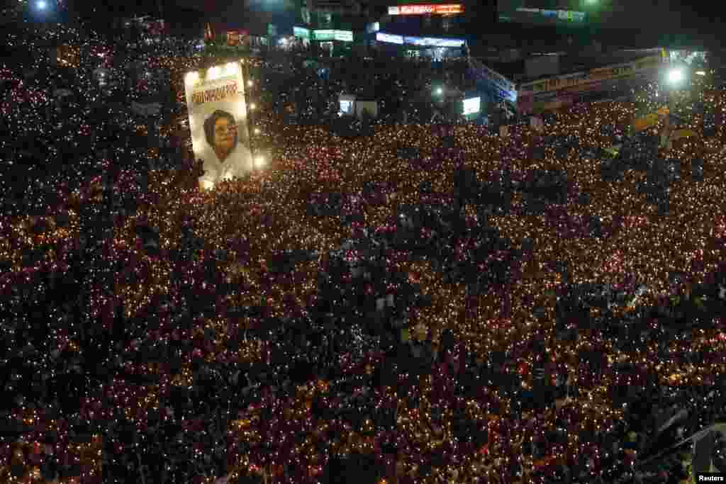 People attend a mass candlelight vigil around a portrait of Jahanara Imam, the late political activist pioneer widely known to bring the accused of committing war crimes in the Bangladesh Liberation War to trial, at Shahbagh intersection in Dhaka, Bangladesh.