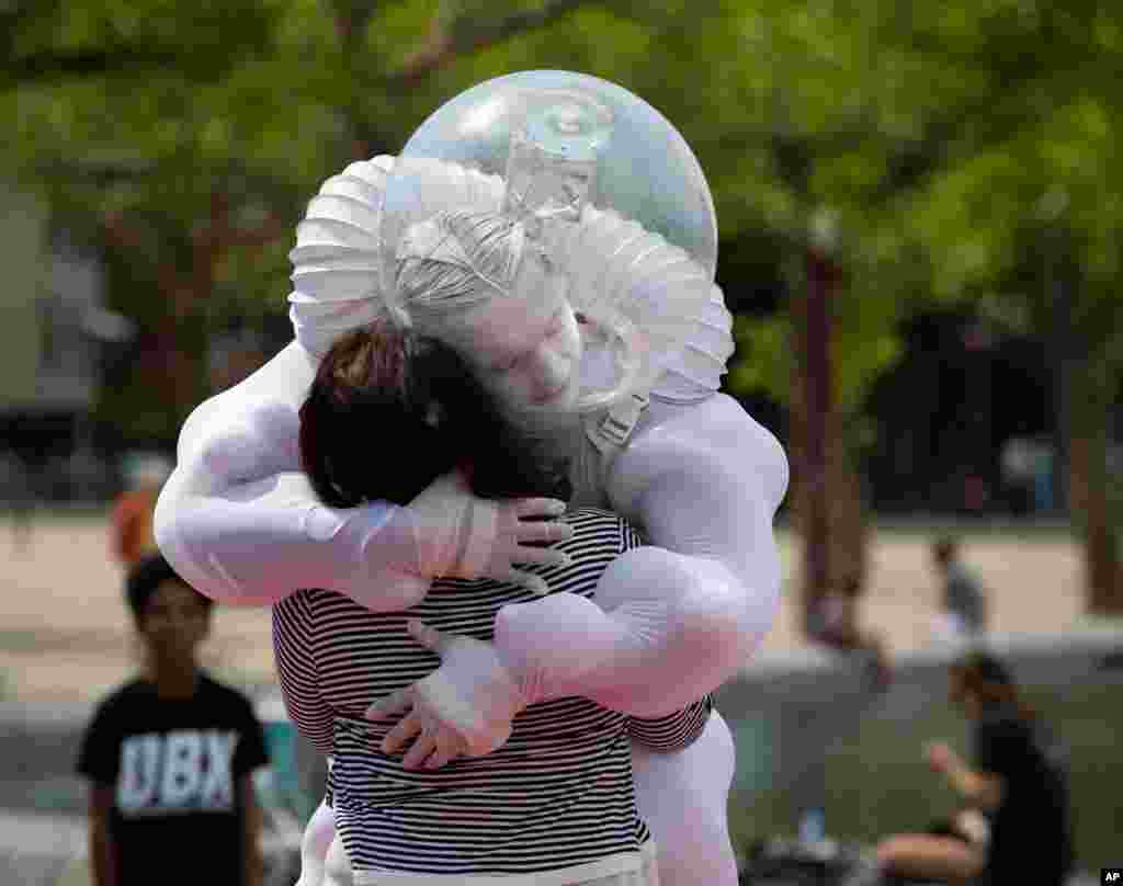 A tourist gets an &quot;Art Hug&quot; from a disinfected costumed man outside the reopened Rijksmuseum in Amsterdam, Netherlands.