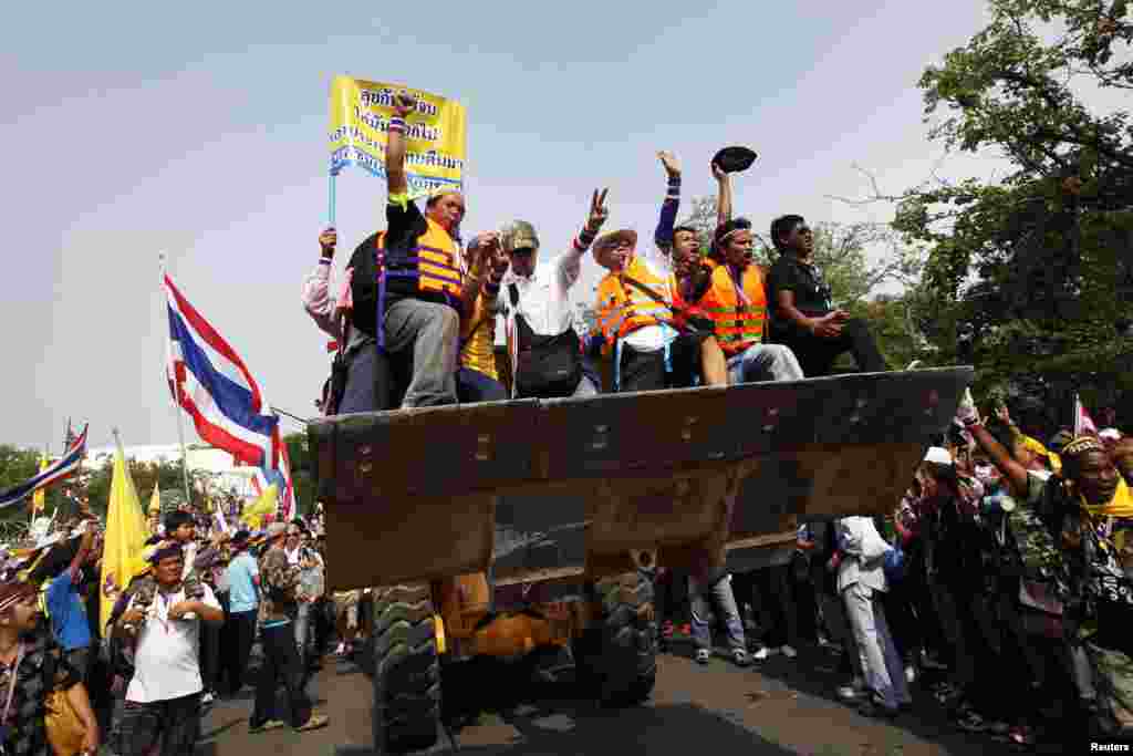 Anti-government protesters celebrate on a front loader used to knock down a concrete barricade outside the Government House in Bangkok Dec. 9, 2013. 