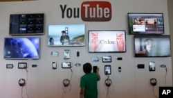 FILE - A man looks at a device at the YouTube booth at Google I/O 2013 in San Francisco.