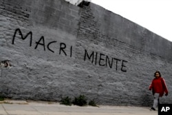 A woman walks past a wall spray-painted with a message that reads in Spanish "Macri lies" in reference to the country’s president, Mauricio Marci, in Buenos Aires, Argentina, Aug. 30, 2018. Argentina's Central Bank on Thursday increased its benchmark interest rate to 60 percent, the world's highest.