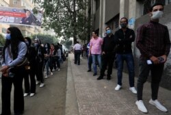 Women and men wait in separate lines to cast their votes, outside a school used as a polling station during the second round of Egypt's parliamentary election in Cairo, Egypt, Nov. 7, 2020.