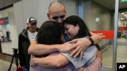 Sean Ours, center, who lives in Alexandria, VA, and Emily Reid, right who lives in Raleigh, NC, embrace for the first time their biological mother Sara Melgarejo upon their arrival at the airport in Santiago, Chile, Sunday, Feb. 18, 2024.