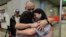 Sean Ours, center, who lives in Alexandria, VA, and Emily Reid, right who lives in Raleigh, NC, embrace for the first time their biological mother Sara Melgarejo upon their arrival at the airport in Santiago, Chile, Sunday, Feb. 18, 2024.