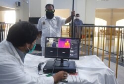 Pakistani railway staff use thermal scanner to check visitors for coronavirus symptoms at Lahore railway station in Pakistan, May 6, 2020.