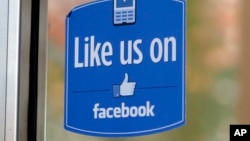 FILE - a sign with Facebook's "Like" logo is posted at Facebook headquarters near the office for the company's User Operations Safety Team in Menlo Park, Calif. 