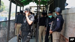 Police officers gather at an entry gate of district court following the killing of a man in court accused of insulting Islam, in Peshawar, Pakistan, July 29, 2020.