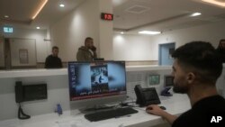 FILE - A staff member at Ibn Sina Hospital shows a news broadcast of security camera footage showing a deadly Israeli military raid in the West Bank town of Jenin, January 30, 2024