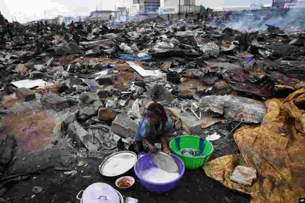 A girl washes the lid of a cooking pot amid the ruins of a market destroyed by city officials in Benin's main city of Cotonou November 17, 2011. Vendors and local residents said police used bulldozers and razed the local market in an effort to tidy the ci