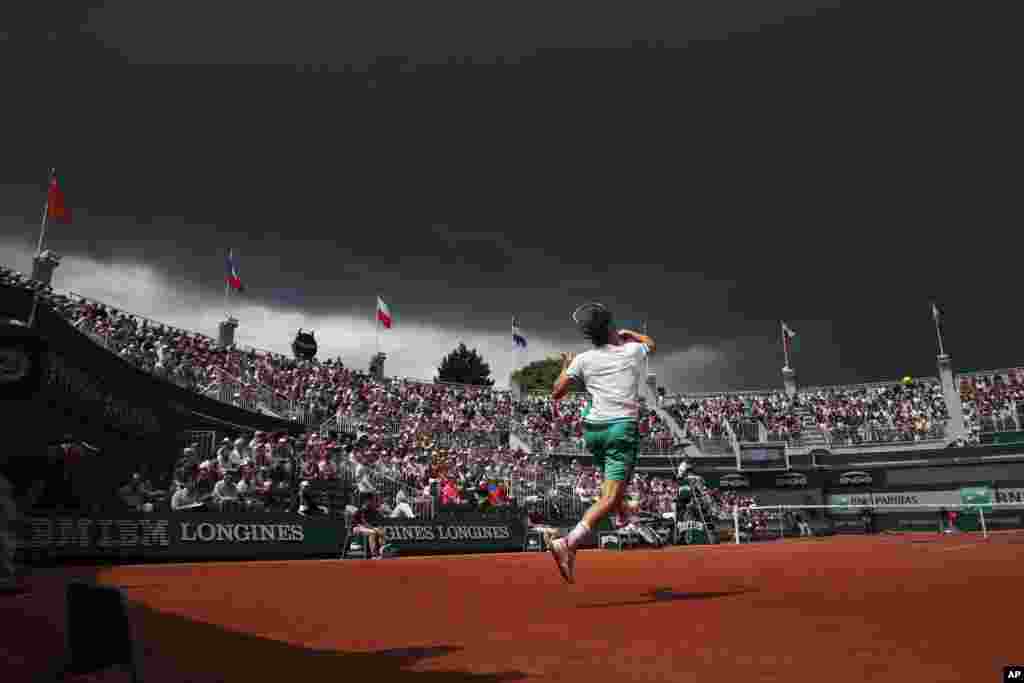 Dark clouds approach court one as Austria&#39;s Dominic Thiem plays a shot against Steve Johnson of the U.S. during their third round match of the French Open tennis tournament at the Roland Garros stadium, in Paris, France.
