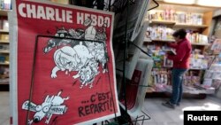 FILE - The front page of the new issue of satirical French weekly Charlie Hebdo entitled "C'est Reparti" ("Here we go again"), is displayed at a kiosk in Nice, Feb. 25, 2015. 