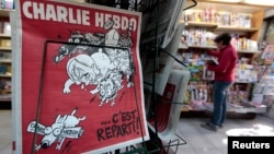 The front page of the new issue of satirical French weekly Charlie Hebdo entitled "C'est Reparti" ("Here we go again"), is displayed at a kiosk in Nice, Feb. 25, 2015. 