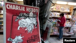 FILE - The front page of an issue of the satirical French weekly Charlie Hebdo entitled "C'est Reparti" ("Here we go again"), is displayed at a kiosk in Nice, Feb. 25, 2015. 