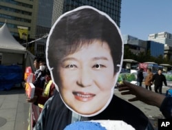 FILE - A South Korean protester wears a mask of South Korean President Park Geun-hye during a rally calling for Park to step down in downtown Seoul, South Korea, Nov. 11, 2016.