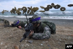 South Korean Marines take position on a beach as amphibious assault vehicles fire smoke shells during a joint landing drill by U.S. and South Korean Marines in the southeastern port of Pohang, April 2, 2017.