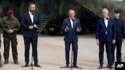 FILE - Poland's Prime Minister Donald Tusk, center, Defense Minister Wladyslaw Kosiniak-Kamysz, center left, and Interior Minister Tomasz Siemoniak, visit troops patrolling the border with Belarus, in Dubicze Cerkiewna, eastern Poland, May 29, 2024. 